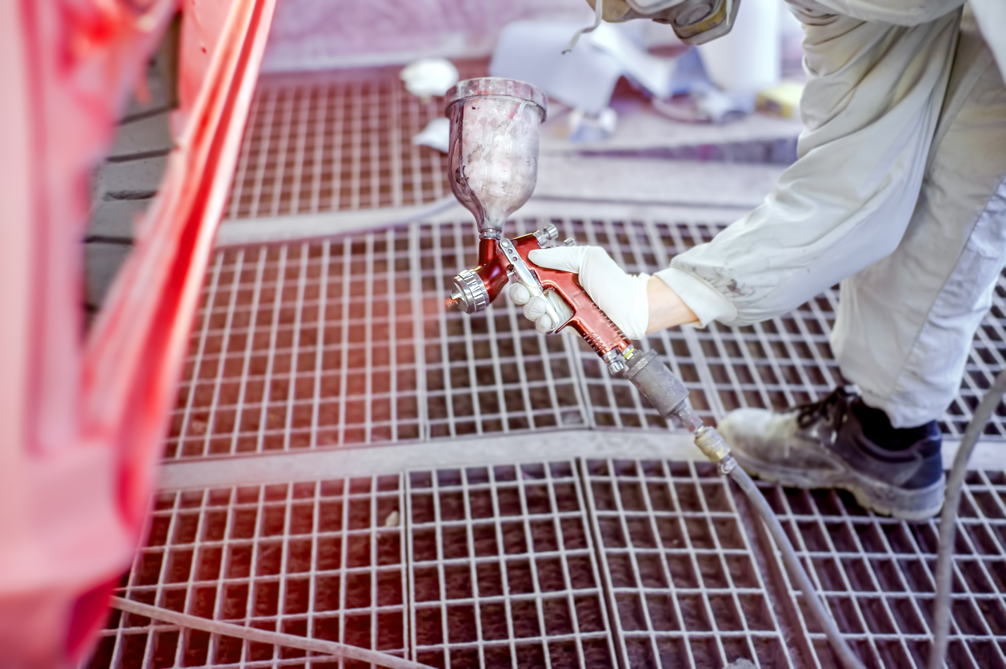 worker-spraying-red-paint-on-body-of-a-2023